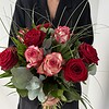 Rosenzauber Rote und rosafarbene Rosen mit feinen Gräsern und ausgewähltem Grün.